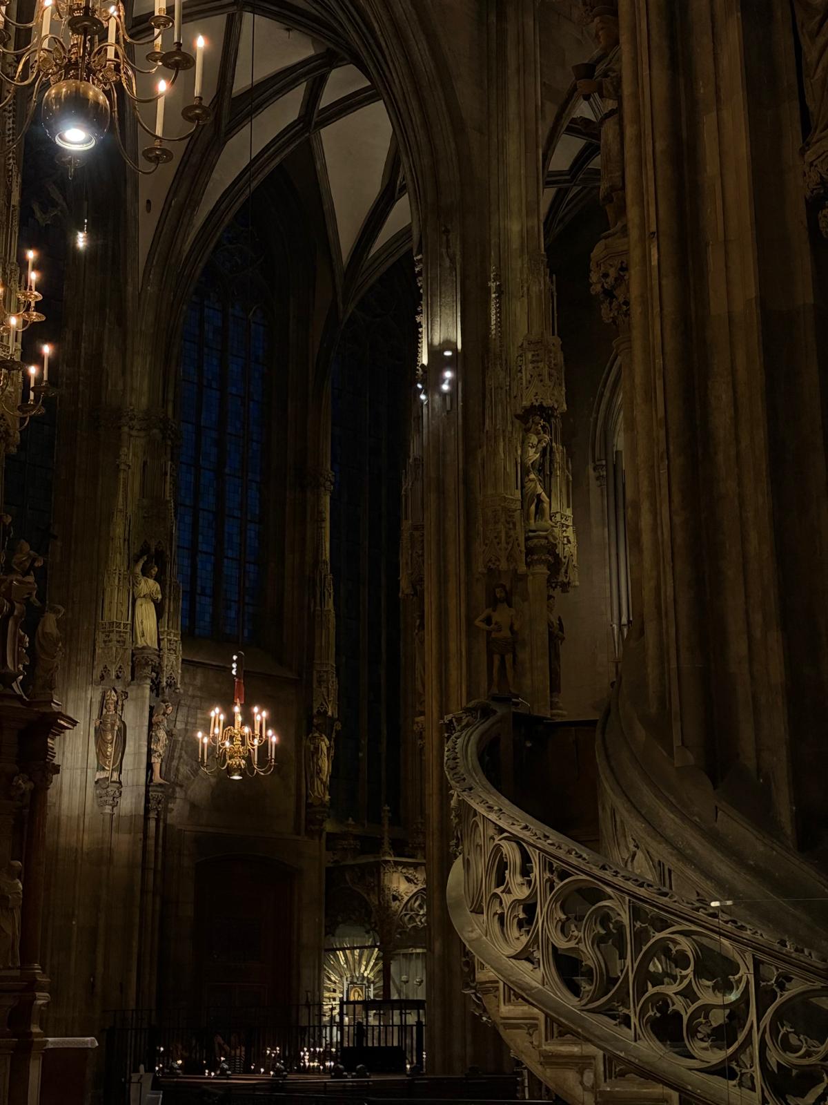 A church interior in Vienna, with Gothic arches, chandeliers and a carved stone staircase